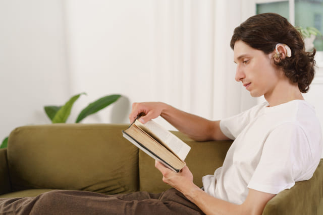 補聴器をつけて本を読む若い男性