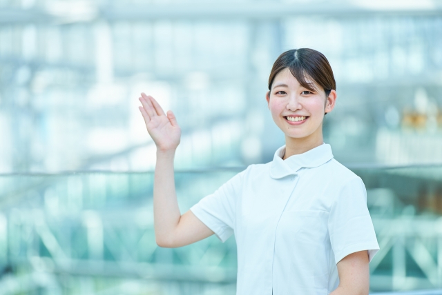 明るく手を振る看護師の女性