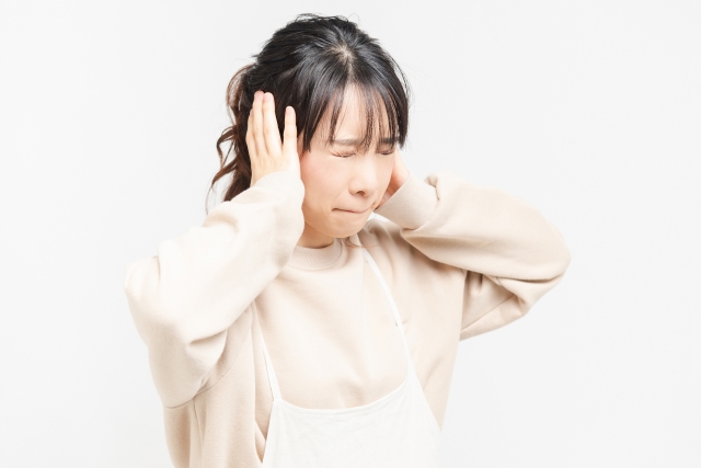 耳を塞ぐ仕草の笑顔の女性
