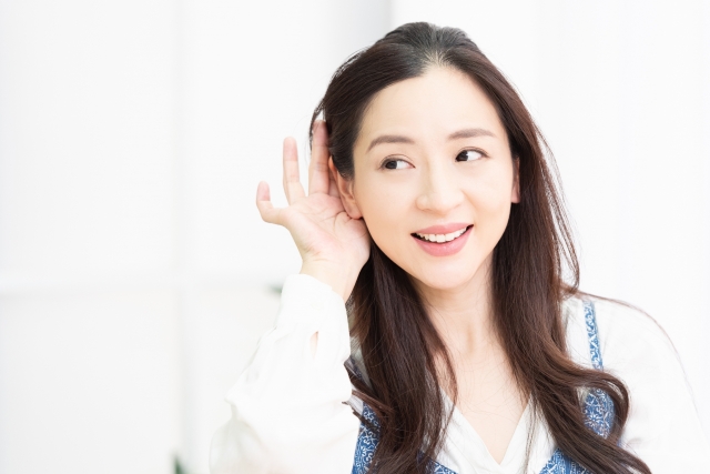 耳に手をかざす笑顔の若い女性